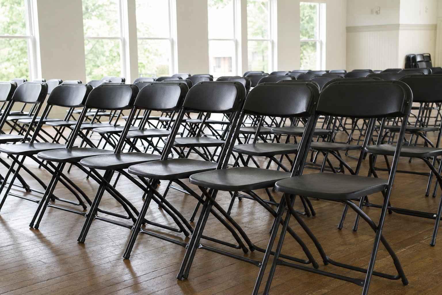 A neat row of sturdy commercial heavy-duty folding chairs set up in a bright community hall