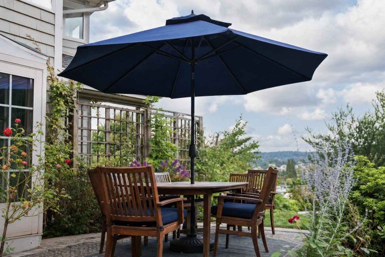 An open patio umbrella with a vented top over a patio set on a breezy day