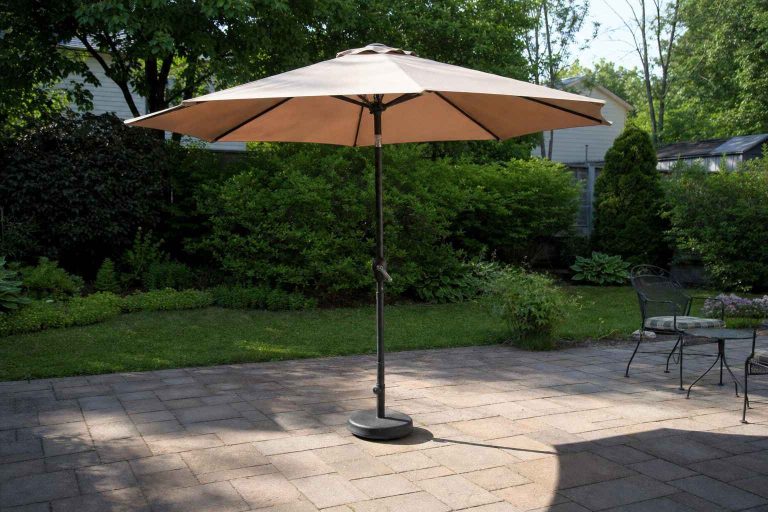 A freestanding patio umbrella on a backyard patio, held up by a heavy weighted base instead of a table