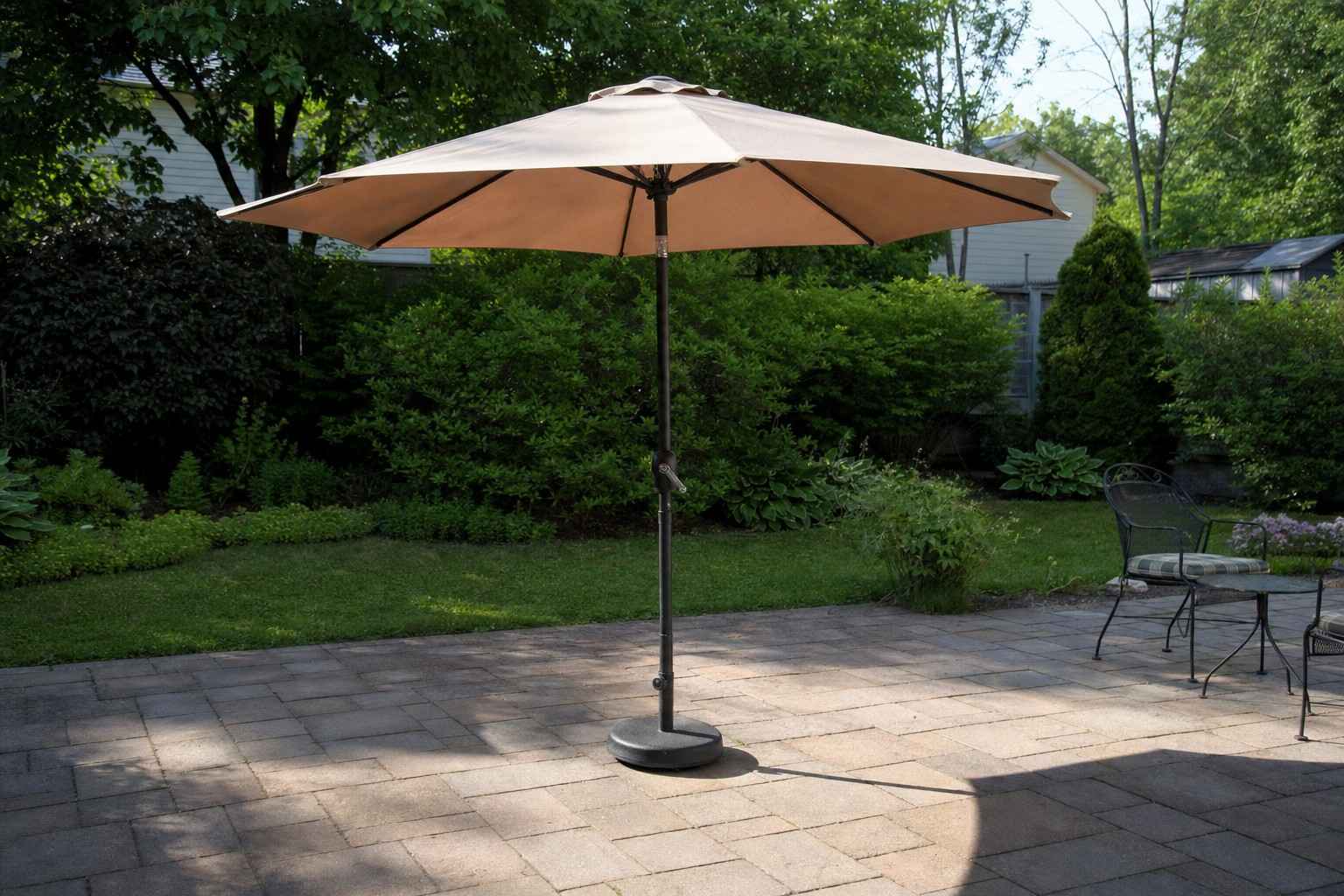 A freestanding patio umbrella on a backyard patio, held up by a heavy weighted base instead of a table