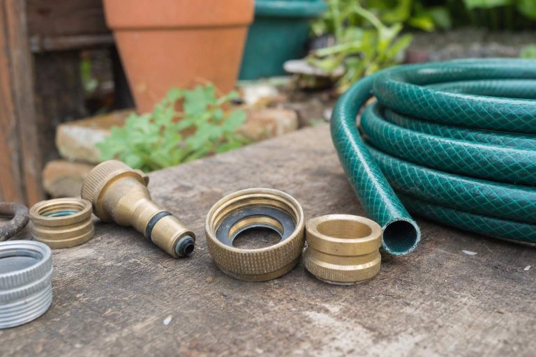 Close-up of brass garden hose fittings and connectors on a green hose