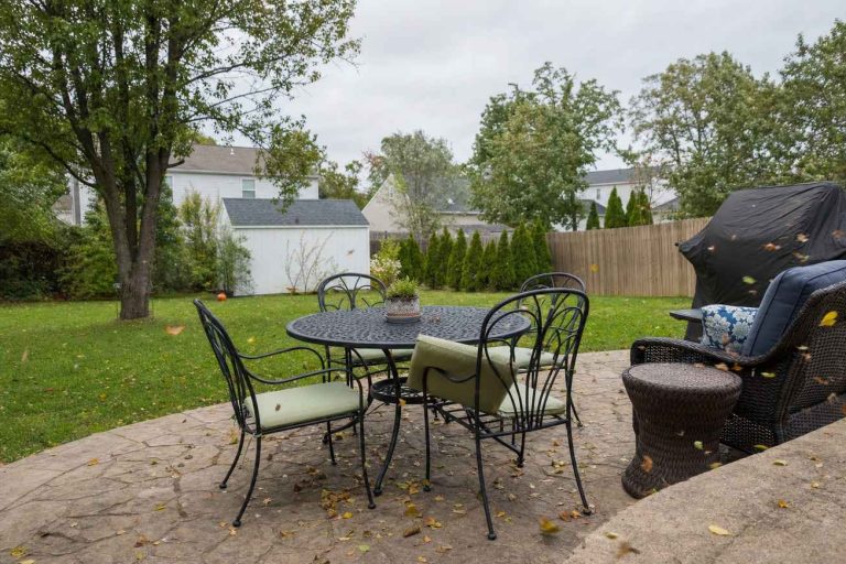Outdoor patio furniture on a windy day with leaves blowing across the patio