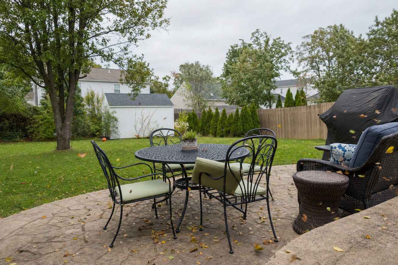 Outdoor patio furniture on a windy day with leaves blowing across the patio