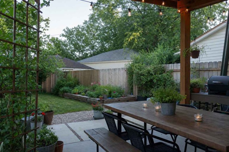 A backyard patio decorated for a casual party with string lights and a set table