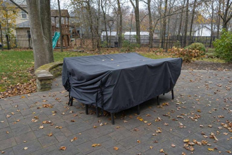 Patio dining furniture protected under a fitted waterproof cover on a late autumn morning