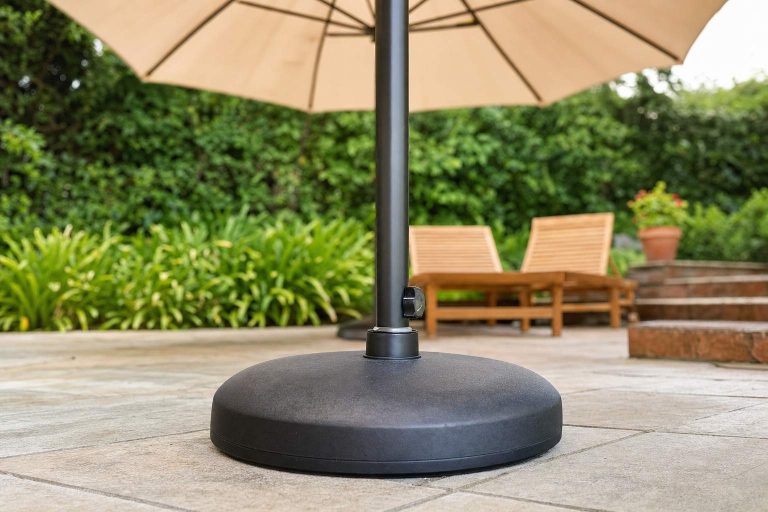 A heavy round umbrella base holding a market umbrella pole steady on a stone patio