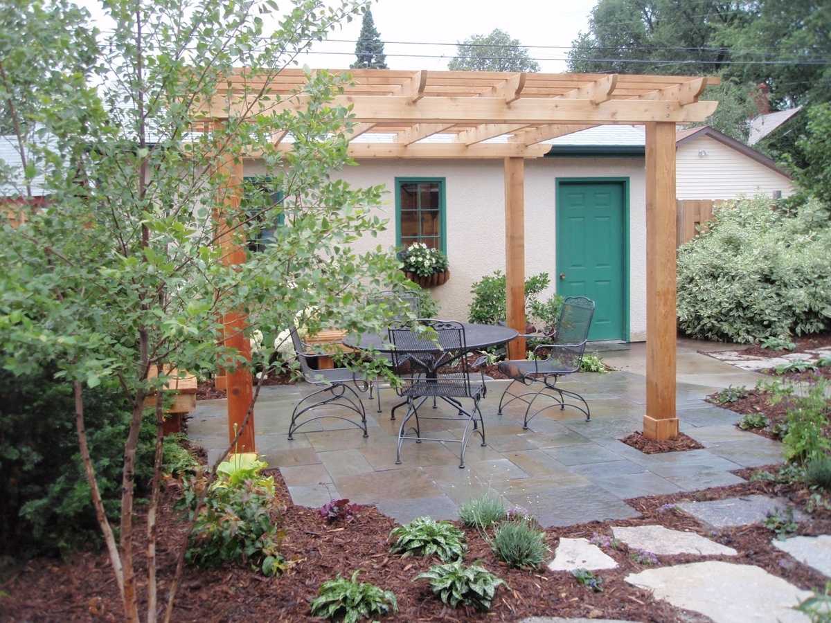 Cedar pergola over a bluestone patio with a wrought iron table and chairs