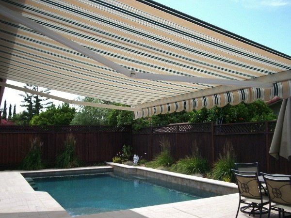 Striped retractable awning shading a swimming pool and patio chairs