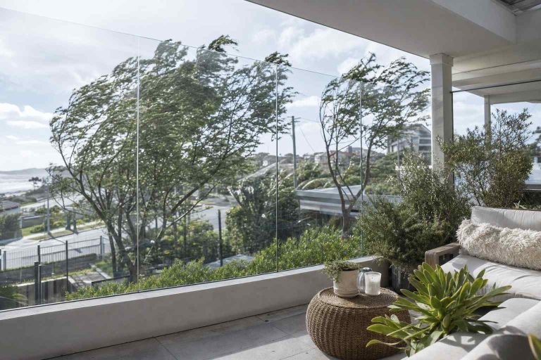 A glass wind screen sheltering a patio seating corner on a breezy day