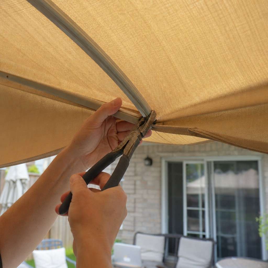Hands straightening a bent aluminum umbrella rib under the open canopy