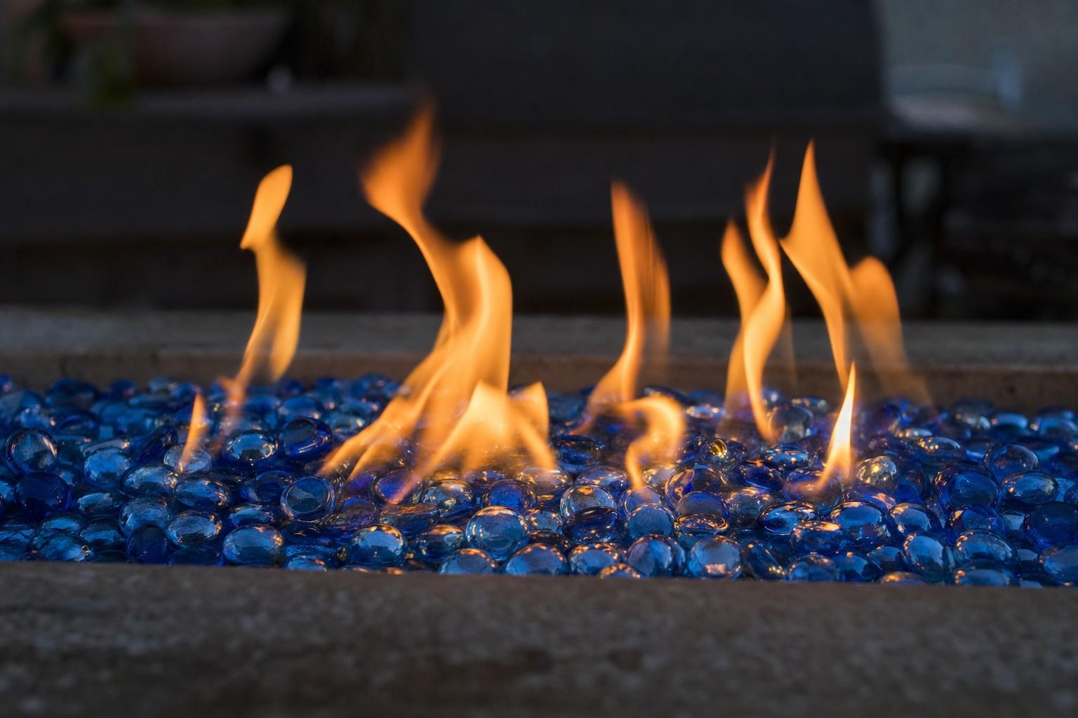 Blue fire glass beads glowing with small flames in a gas fire pit