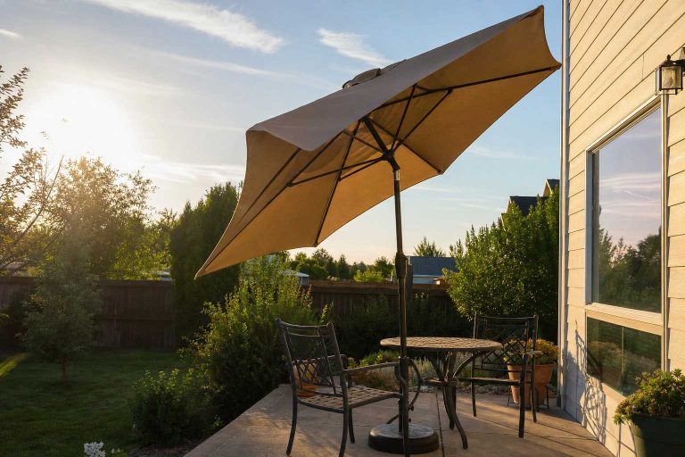 A patio umbrella tilted against low afternoon sun over a small table