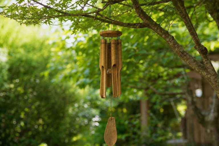 A bamboo wind chime hanging from a garden tree branch